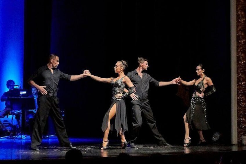 Une représentation de danse sur une scène, avec quatre danseurs vêtus de noir. 4