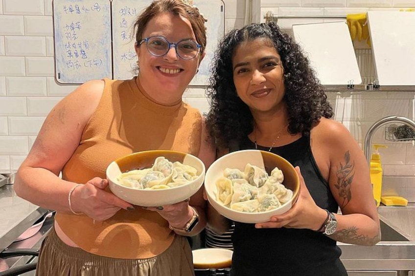 Twee mensen houden schalen met eten vast in een keuken. 2