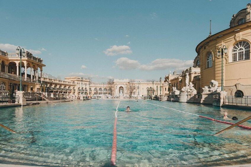 A large outdoor swimming pool with clear blue water, surrounded by classical architecture. 4