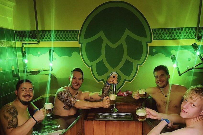 A group of people in a room with a large leaf-shaped logo on the wall, holding drinks. 3