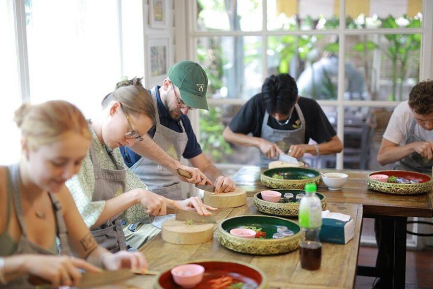 People preparing food at a table with various ingredients and utensils. 2