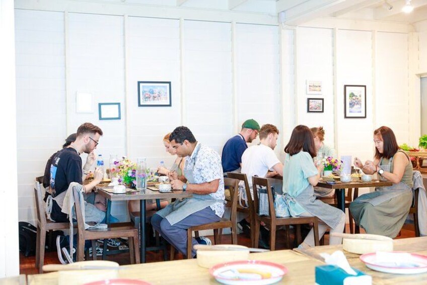 Un groupe de personnes est assis à une table dans un restaurant, les tables et les chaises étant en bois. 2