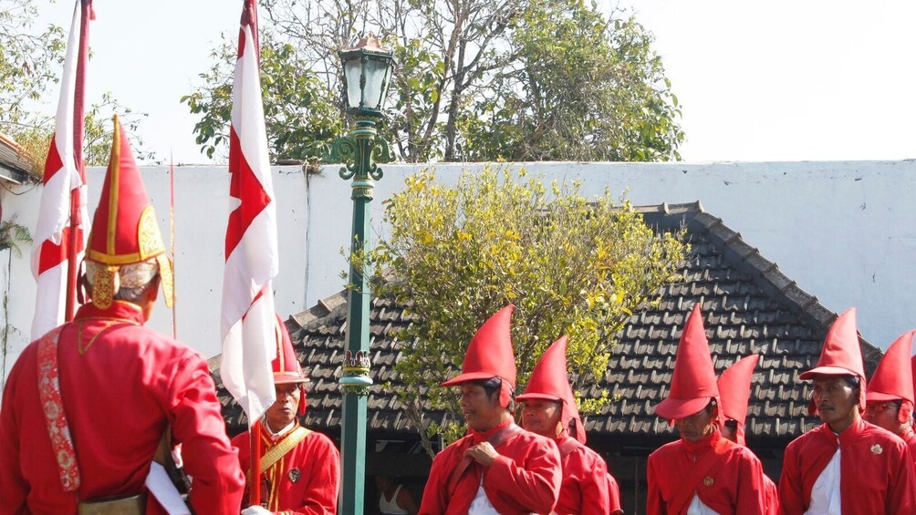 A group of people in red uniforms and pointed hats, possibly in a parade or ceremonial event. 2