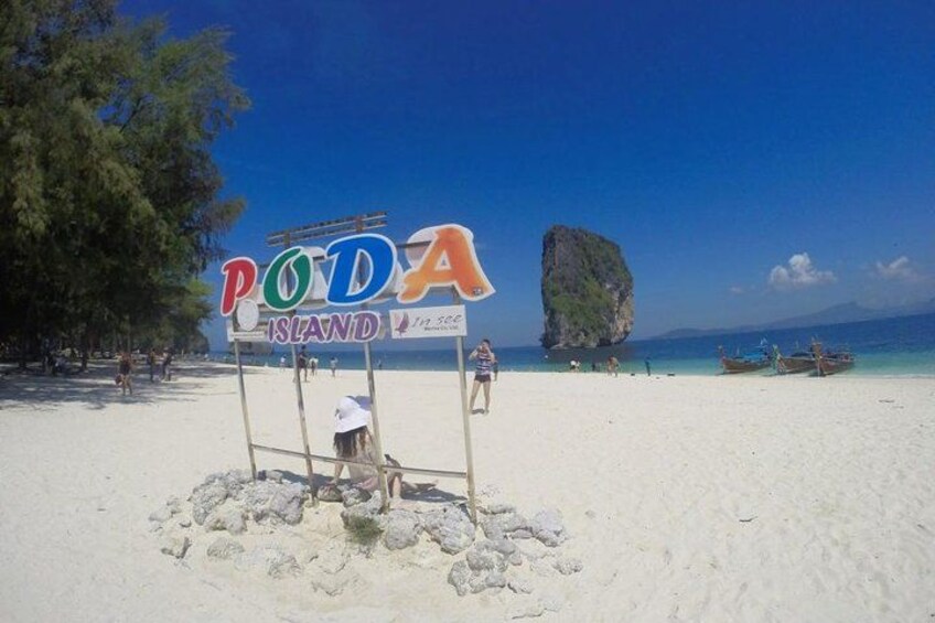 A beach with a sign reading "PODA ISLAND" and a large rock formation in the background. 5