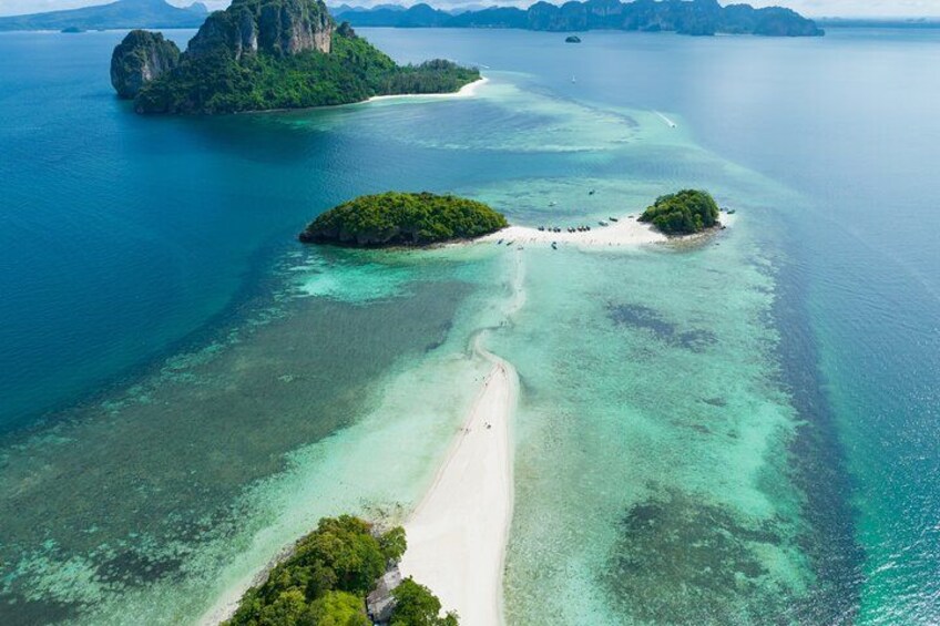 An aerial view of a tropical island with clear turquoise waters, a sandy beach, and lush green vegetation. 1