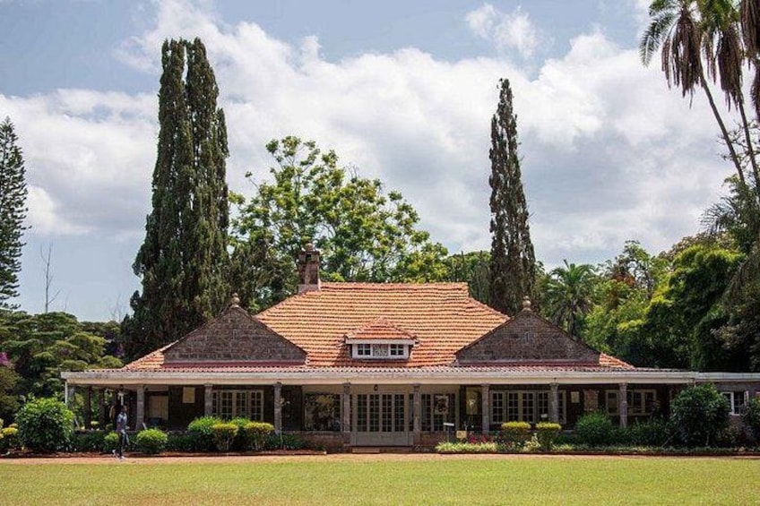 A large house with a tiled roof, surrounded by a well-maintained lawn and tall trees. 4