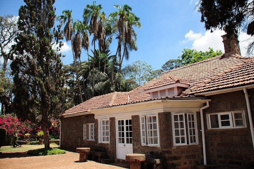 A brick house with a tiled roof, surrounded by trees and a garden. 3