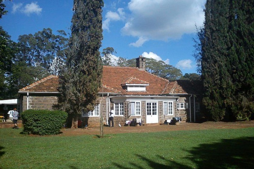 A stone building with a tiled roof, surrounded by grass and trees. 1