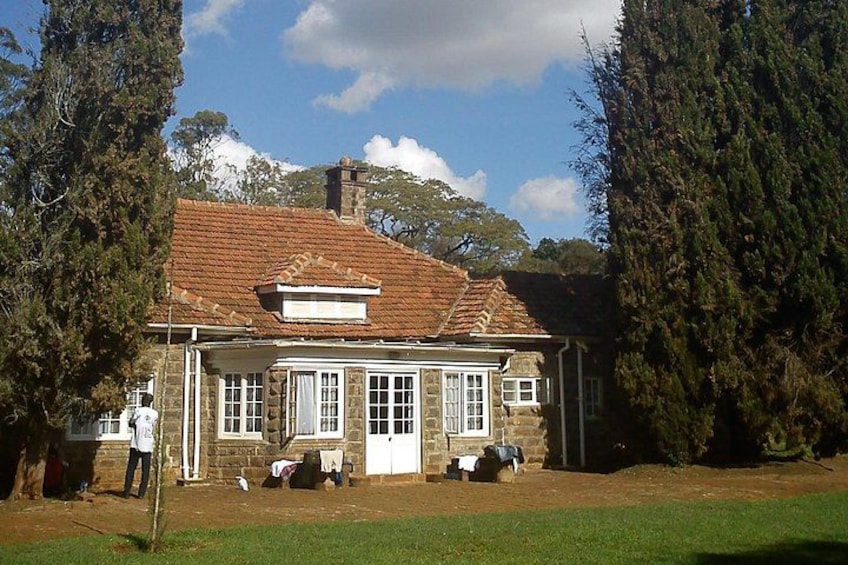 A stone house with a tiled roof, surrounded by trees and a grassy area. 5