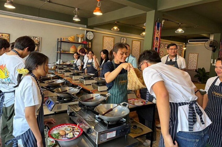 A kitchen with multiple chefs preparing food, cooking stations, and kitchen equipment. 2