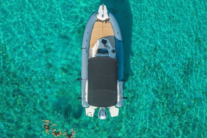 An aerial view of a small boat on clear turquoise water. 1