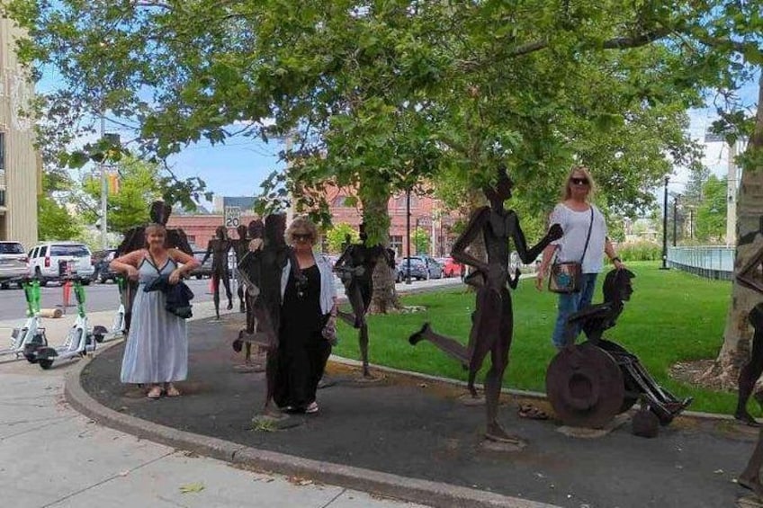 A group of people walking on a sidewalk with trees and a street in the background. 2