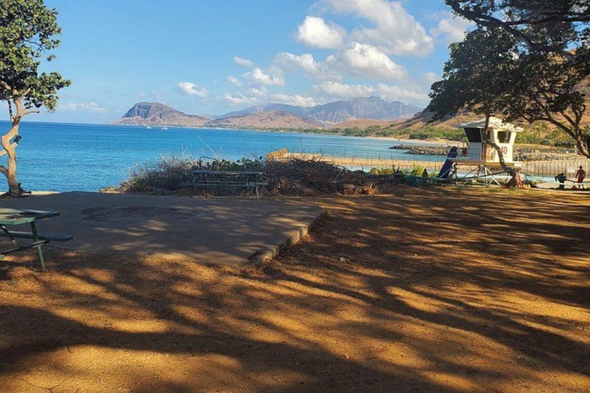 Une plage avec un poste de surveillance pour les sauveteurs, une mer d’un bleu limpide et des montagnes à l’horizon. 1