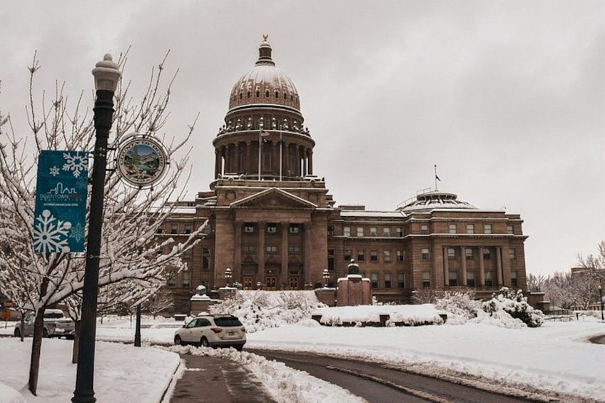 A large government building with a dome, surrounded by snow-covered trees and a clear sky. 4