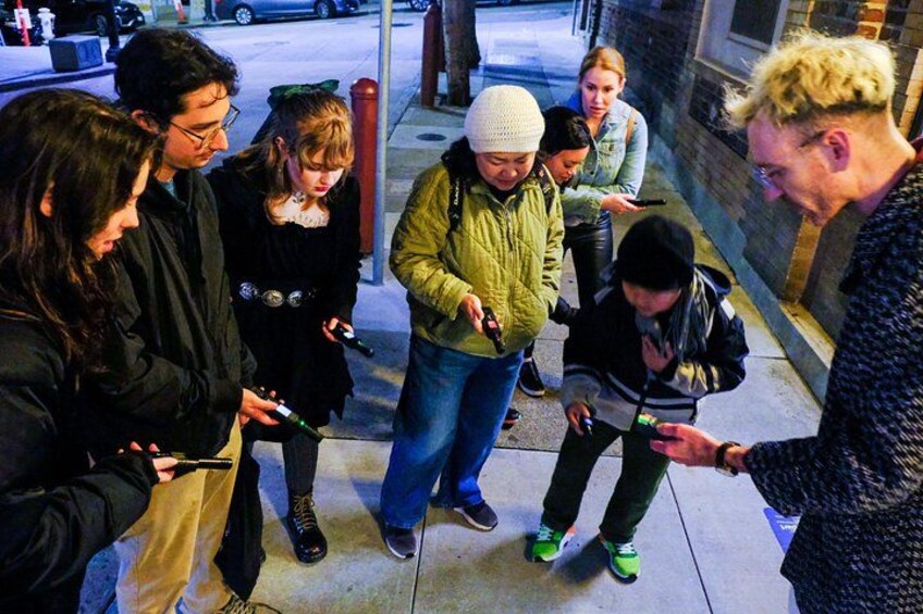 Un grupo de personas de pie en una acera, algunas mirando sus teléfonos. 2