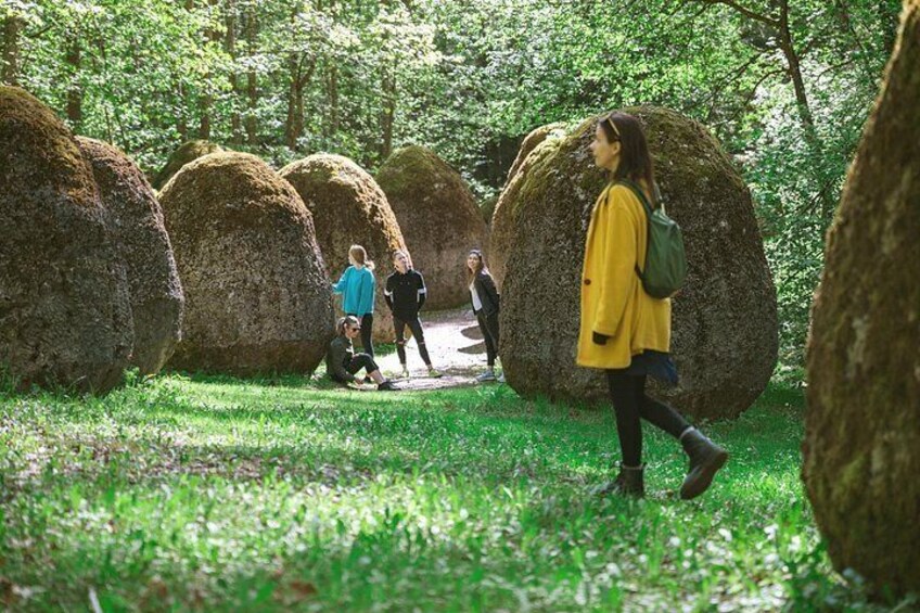 Bosque con grandes rocas esféricas, personas caminando y un sendero. 5