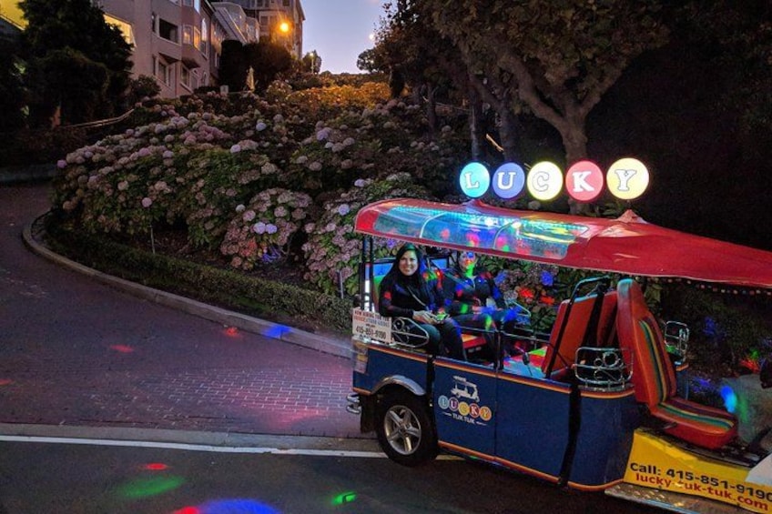 A colorful bus with illuminated letters spelling 'LUCKY' parked on a street. 2