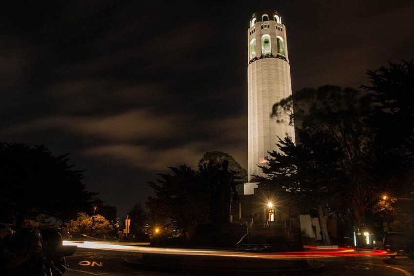 A tall tower with a clock at the top, surrounded by trees and streetlights. 4