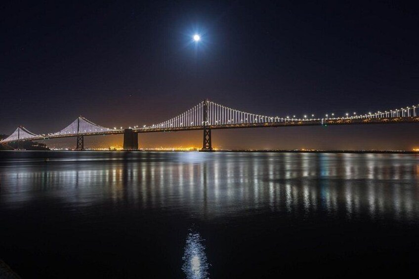 A nighttime view of a bridge with lights reflecting on the water. 5