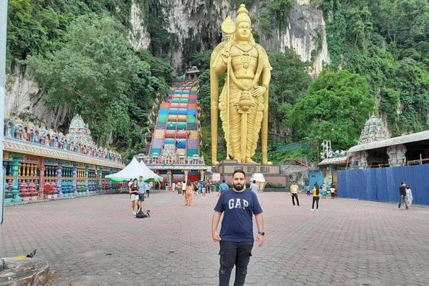 Eine große goldene Statue, ein Tempel mit bunten Stufen und eine Person im Vordergrund. 3