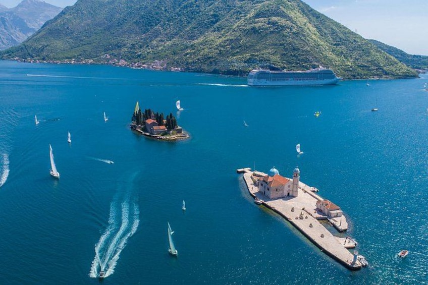 Una extensa masa de agua con un crucero, veleros y una pequeña isla con edificios. 5