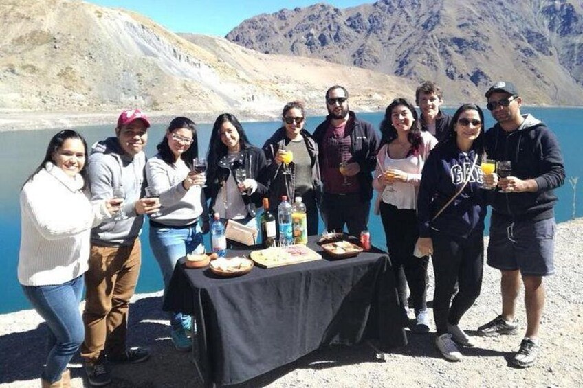 A group of people standing by a table with drinks and snacks, overlooking a mountainous landscape. 3