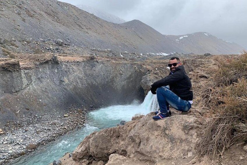 A person sitting on a rocky outcrop by a flowing river in a mountainous area. 2