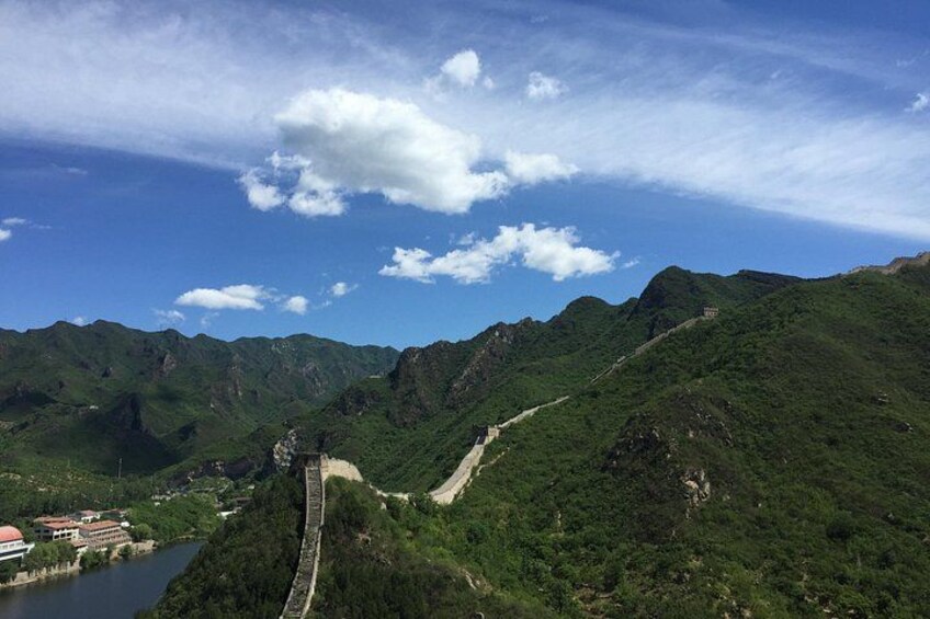 A mountainous landscape with a winding road, a river, and a small settlement. 3