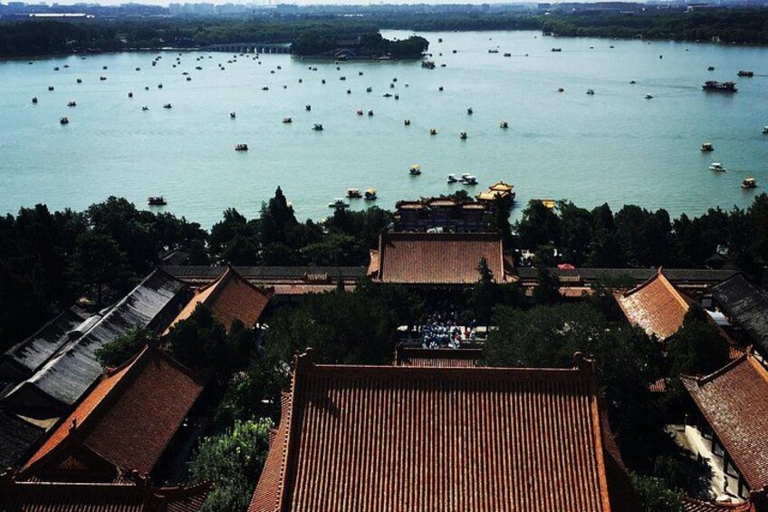 A traditional Chinese architectural complex with tiled roofs, surrounded by a body of water with numerous boats. 2