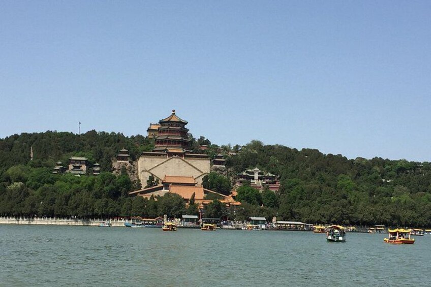 A traditional pagoda on a hill, a body of water with boats, and a forested area. 4