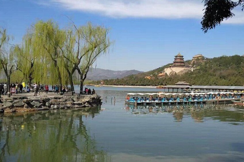 A calm lake with willow trees, a traditional pagoda, and a rowboat with passengers. 5