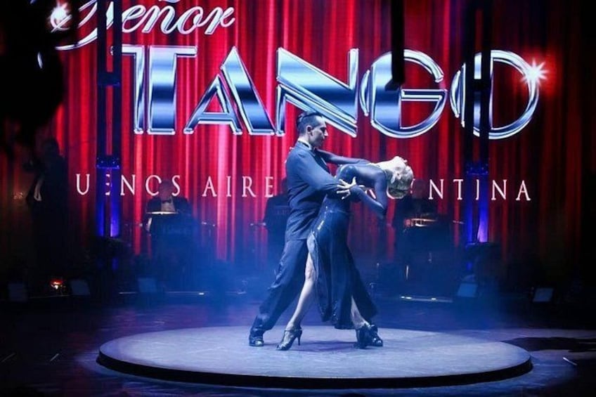 Een dansvoorstelling op een podium, met een rode gordijnenachtergrond en de tekst 'TENOR' en 'TANGO'. 2