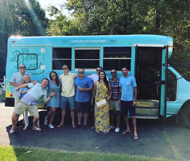 A group of people posing in front of a blue bus with 'RVA Brew Crew' written on it. 2