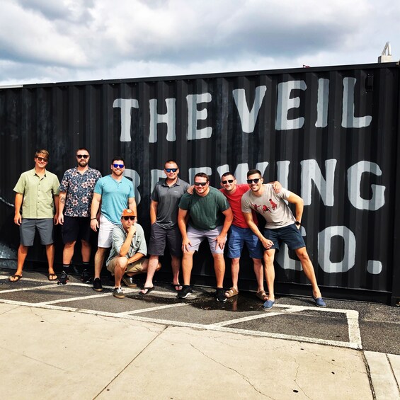 A group of people posing in front of a black container with white text. 3