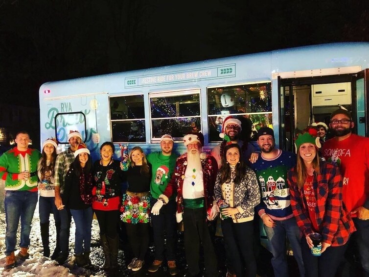 A group of people in festive clothing standing in front of a decorated bus with a sign that reads "Festive Ride for Your Brew Crew". 4