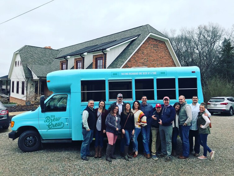 A group of people posing in front of a blue bus with 'Breit Crew' written on it. 1