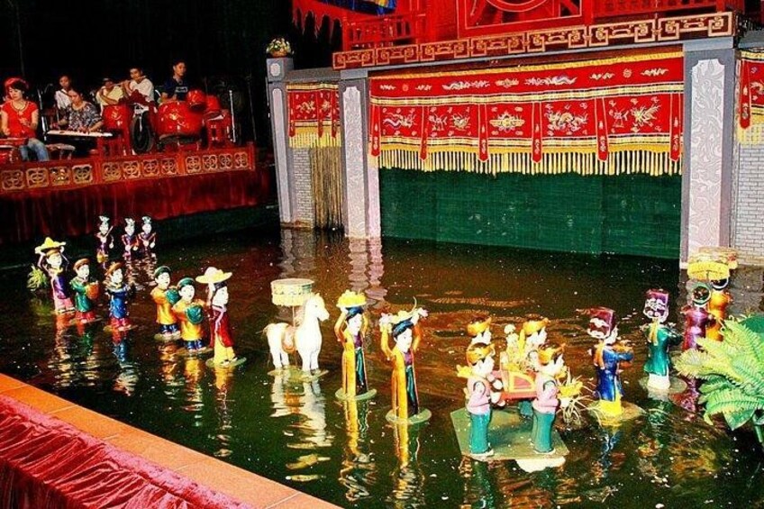 A traditional Chinese water puppet show with performers and puppets on a stage. 1