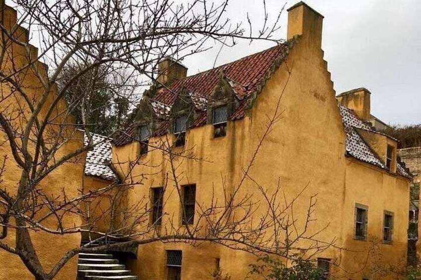 Een geel gebouw met een rode pannendak, omgeven door kale bomen. 3