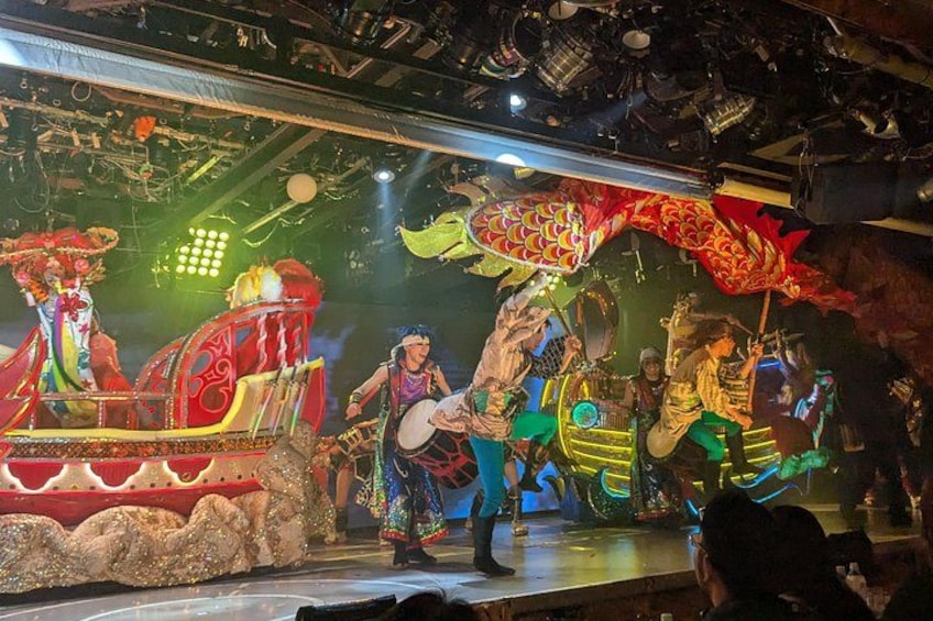 A stage with performers in traditional costumes, a dragon float, and musical instruments. 4