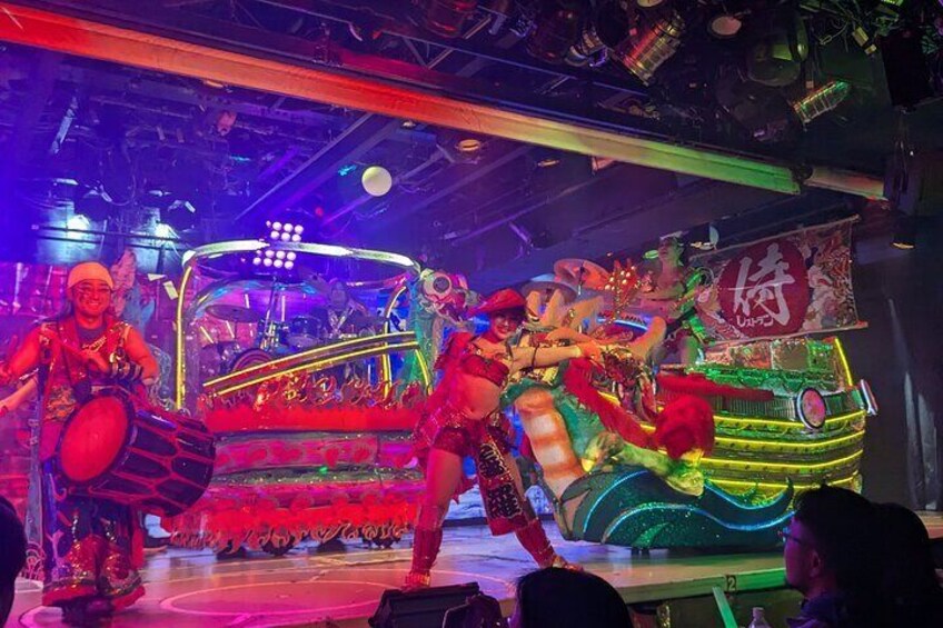A stage performance with performers in colorful costumes and a decorated stage. 1