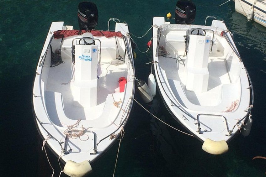 Two white motorboats tied together at a dock. 1