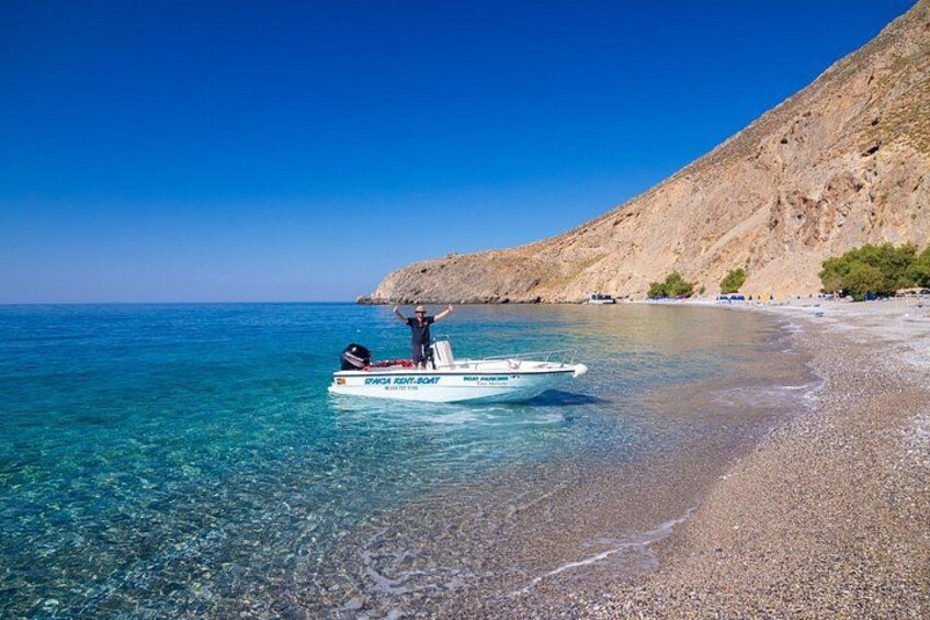A boat on a clear beach with a rocky hillside in the background. 2