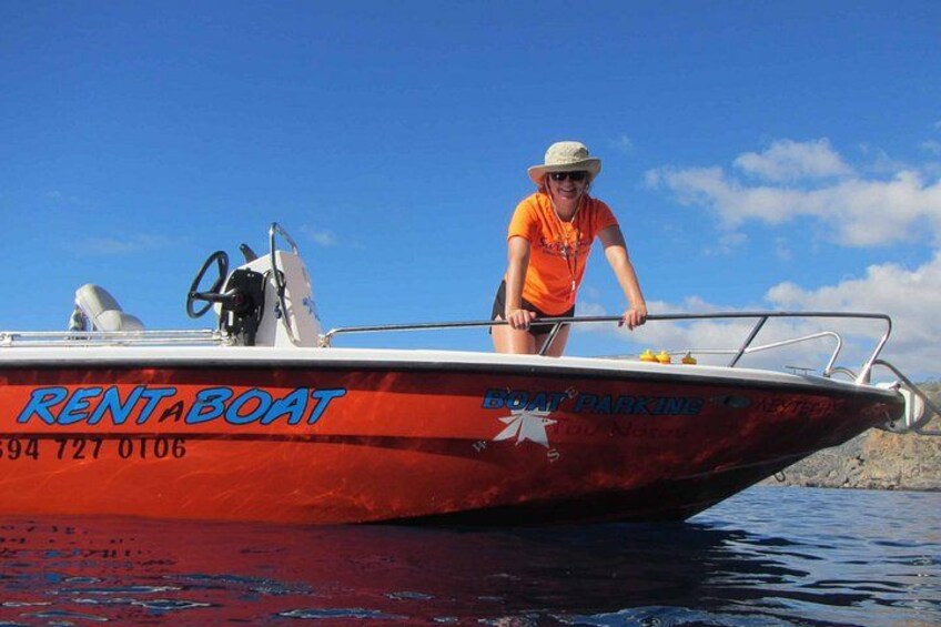 A red boat with 'RENT A BOAT' and 'BOAT PARKING' written on it, a person in an orange shirt, and a clear blue sky. 4