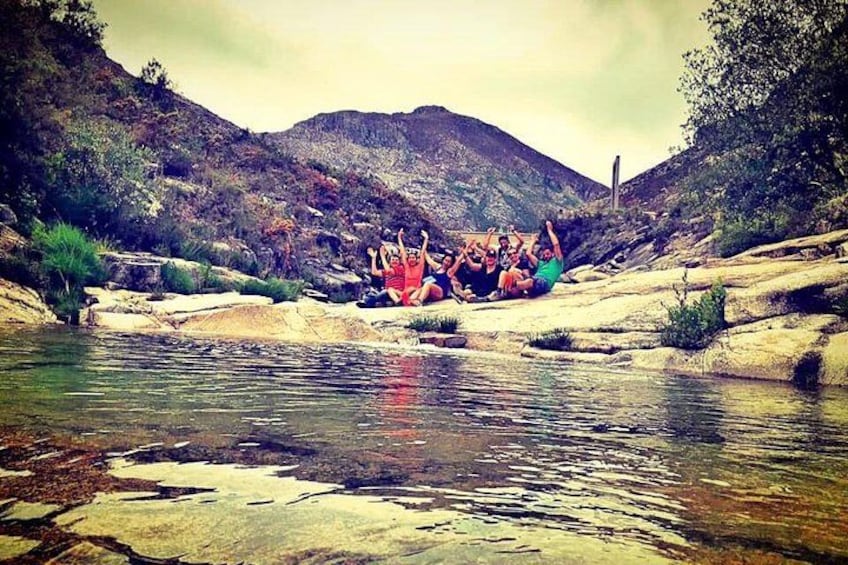 A group of people sitting on rocks by a river. 1