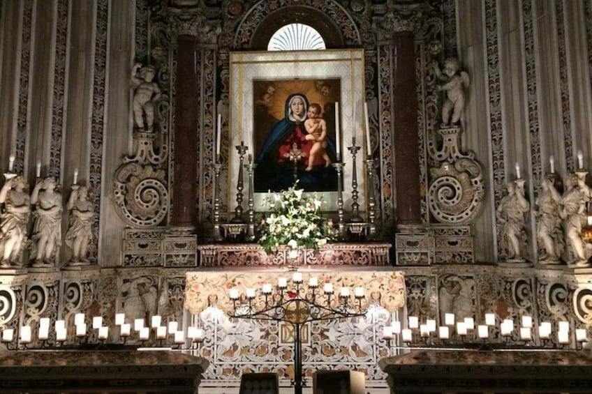 An ornate altar with a religious painting, candles, and statues. 2