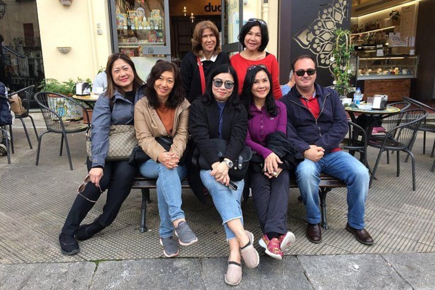 A group of people sitting on outdoor chairs in front of a cafe. 3