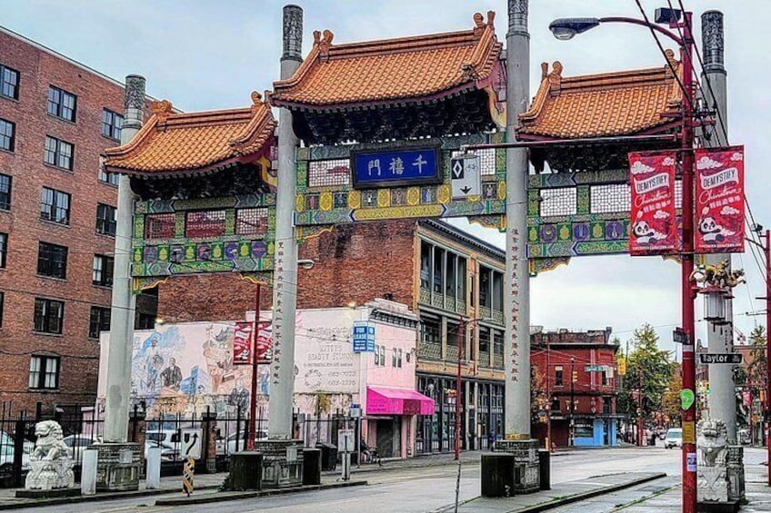 Een traditionele Chinese poort met kleurrijke versieringen, een modern gebouw met een roze luifel, en een straat met verschillende borden en reclames. 4