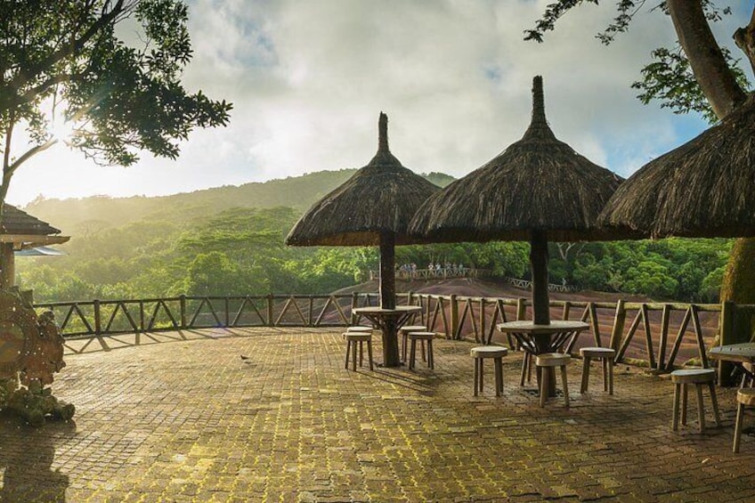 Une terrasse agrémentée de parasols en chaume et de tables en bois, offrant une vue sur un paysage luxuriant. 5