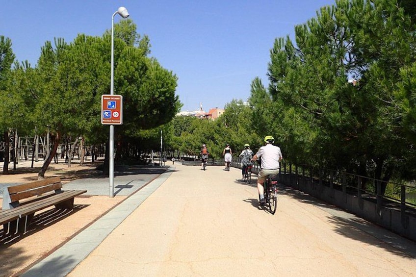 Un chemin pavé, avec des cyclistes, des arbres et un banc. 2