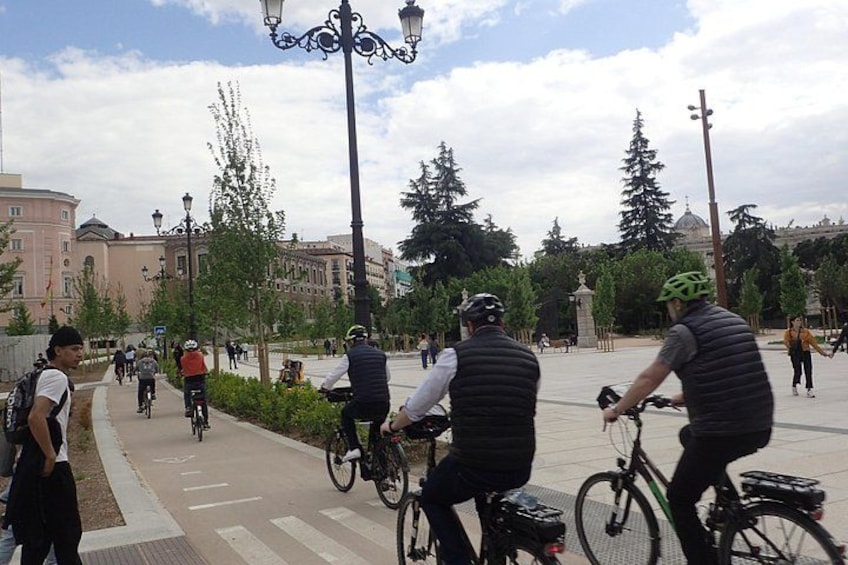 Des cyclistes sur une piste cyclable asphaltée, avec des arbres et des bâtiments en arrière-plan. 3